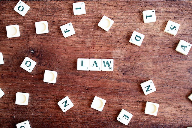 scrabble tiles spelling out the word law on a wooden table